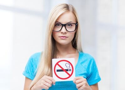Nena que ten un cartel para non fumar na entrada